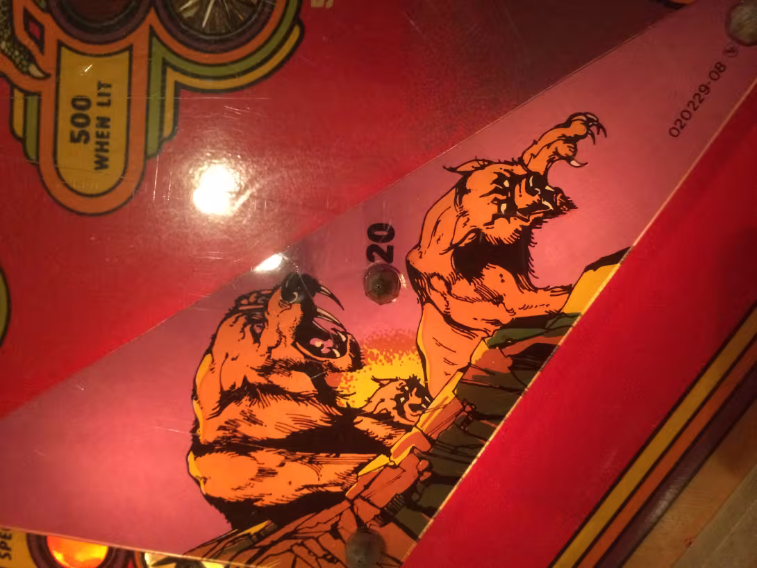 "20" next to some graphics of some saber-toothed cats on a pinball table.